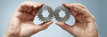 Two interlocking gears are held up by two hands: Expertise of the patent law firm
